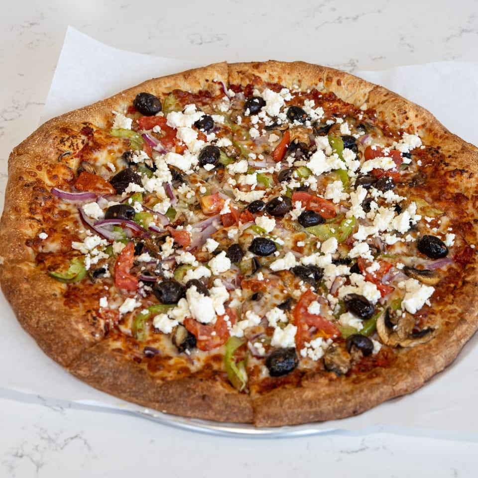 Tastivo Pizza's Greek pizza, topped with feta, olives, tomatoes, onions, and green peppers.